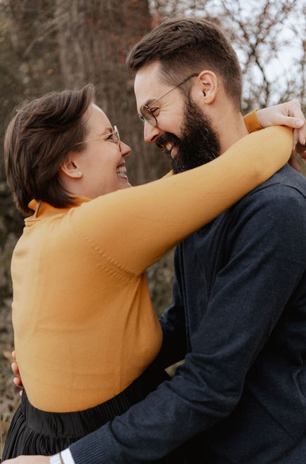 Babybauch und Familienfotos Olching. Ein Paar steht sich gegenüber. Die Frau hat ihre Arme um den Nacken des Mannes gelegt, die beiden lächeln sich an