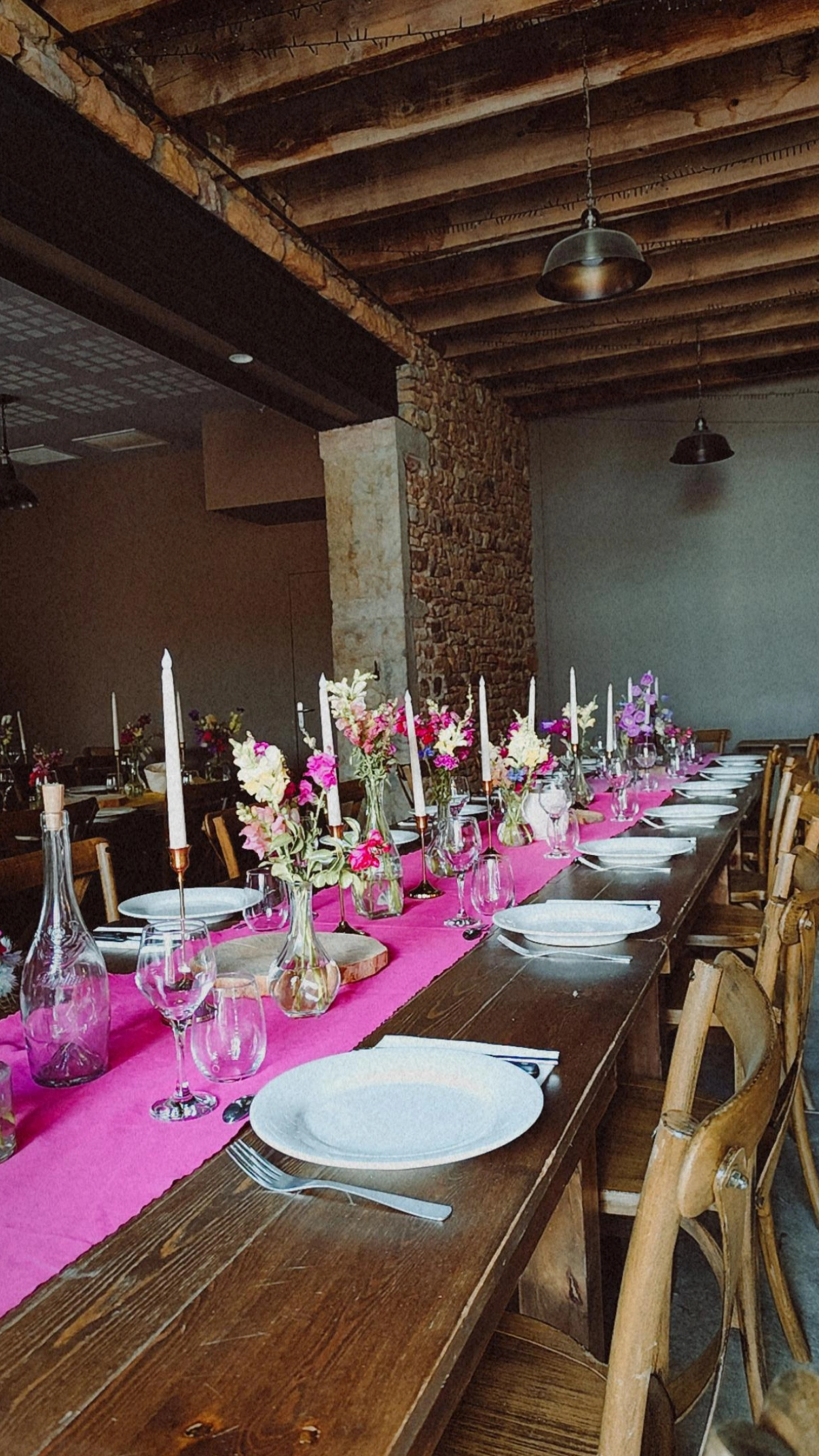 Table de mariage dressée avec chemin de table rose, bougies et fleurs