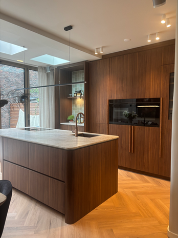 Maatwerk keuken met kookeiland en notenhouten fronten, Hoorn
Kastenwand in donker eiken met verlichte koffienis, Zwaag
Keramisch werkblad in marmerlook op maatwerk keukeneiland
Quooker Flex Round in patinated brass in maatwerkkeuken
