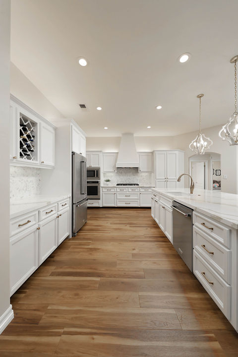 Dreamy white kitchen with Quartz countertops, brass details and detailed flower mosaic backsplash by Code Construction.