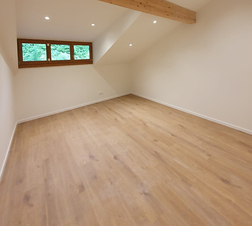Pose de parquet flottant en bois clair dans une chambre — rénovation de sols par MS BAT.