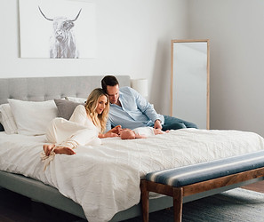 parents with their newborn baby on their bed