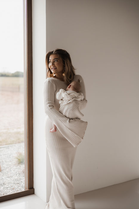 Foto van een moeder die haar baby stevig vasthoudt in haar armen.