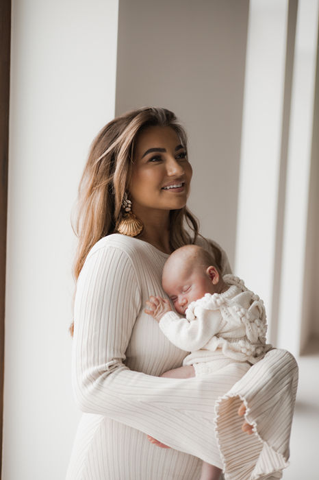 Foto van een moeder die haar baby stevig vasthoudt in haar armen.