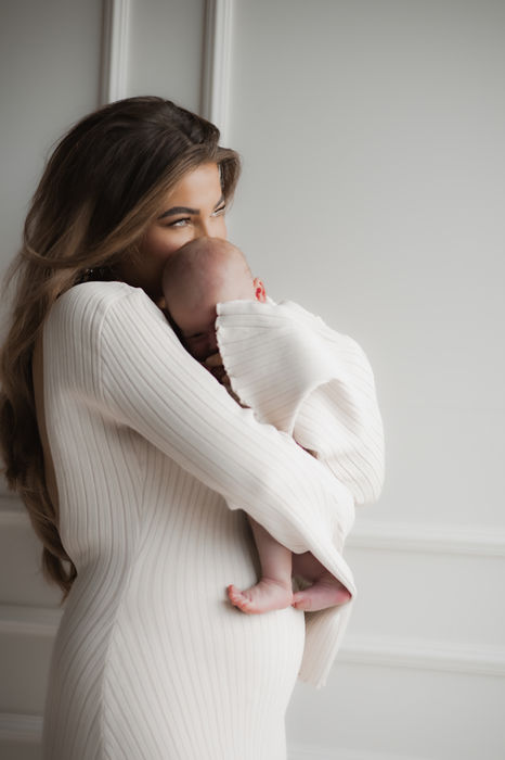 Foto van een moeder die haar baby stevig vasthoudt in haar armen.