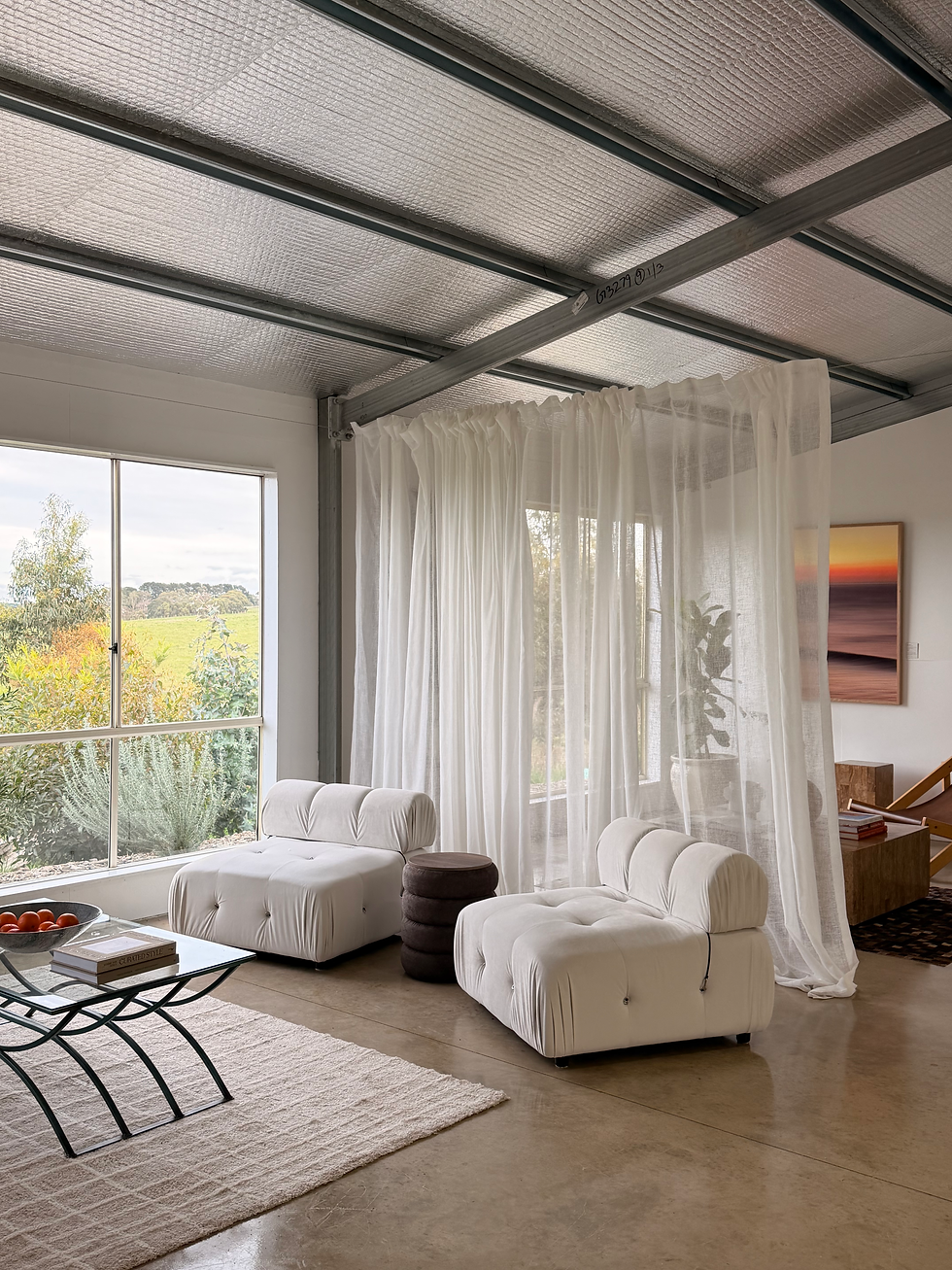 Light-filled studio lounge with white modular sofa and sheer curtains overlooking the valley
