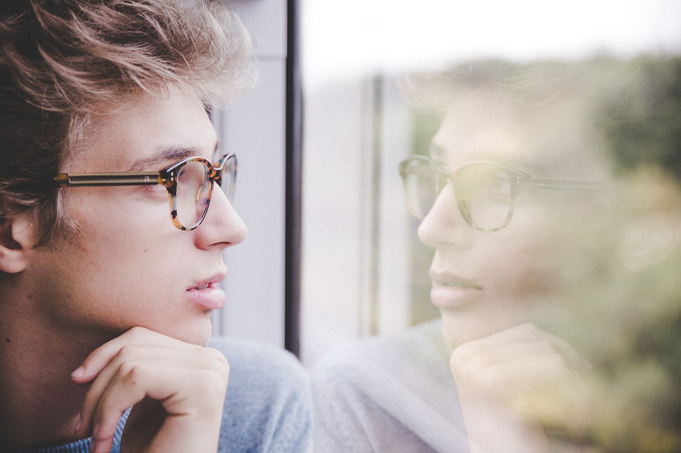 A young man looking out of his bedroom window, considering his future