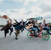 Gruppe fährt auf einem Fahrrad, spielt Gitarre, Presseartikel und Ausschnitte. Fröhliche Menschen.