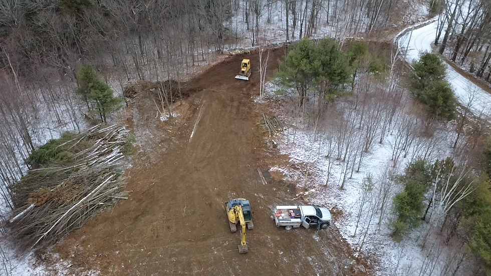 Excavator and truck on a land development site in winter.