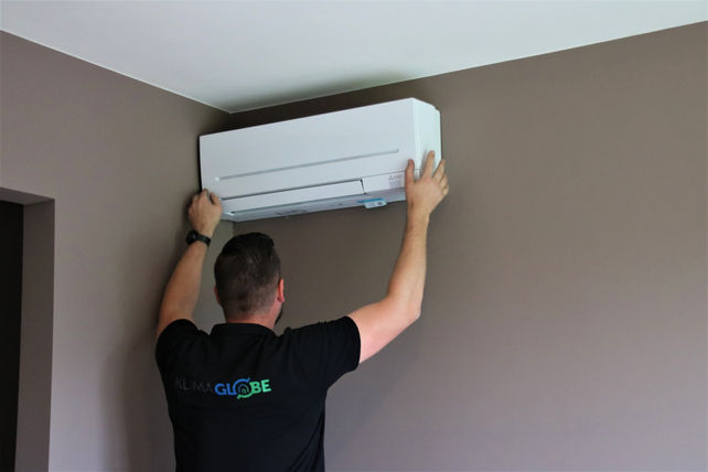 Technieker plaatst airco-binnenunit aan de muur