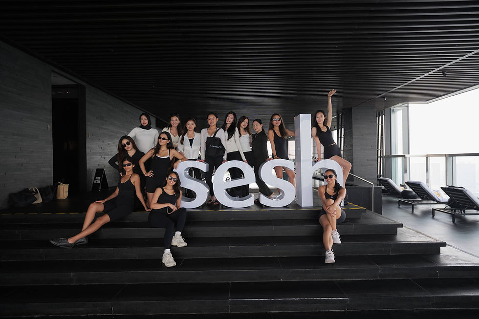 A group of women in black and white outfits poses on steps indoors with large "sesh" letters, creating a stylish, relaxed mood.