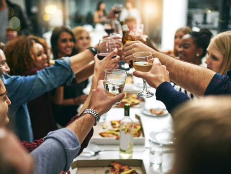 roup of teachers and educators raising glasses in a celebratory toast at a restaurant, enjoying social connection and laughter during their self-care challenge