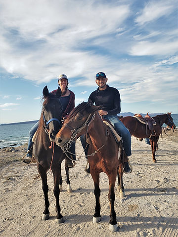 man and women on horses riding on sand near the beach