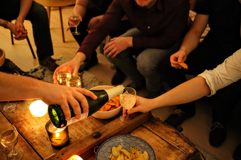 group of people pouring wine eating snacks on wood table
