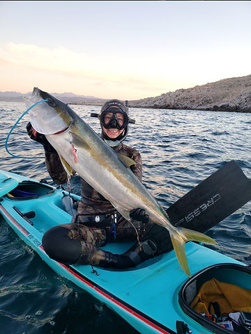 woman with fish spearfishing from kayak in La Paz