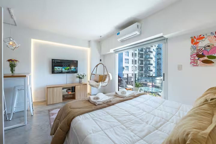 Studio sleeping area with queen bed and natural light from balcony in Palermo Soho