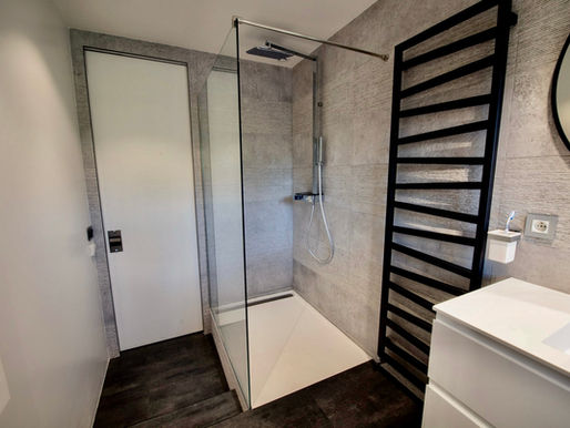 Salle de bain design avec robinetterie noire, sèche-serviettes noir et porte à galandage – 1001 idées