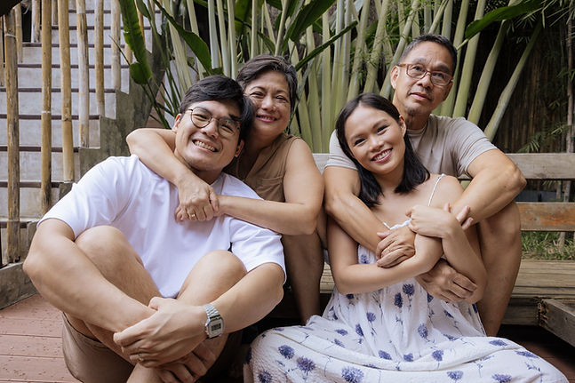 mother and father in their 60s embrace their adult son and daughter from behind