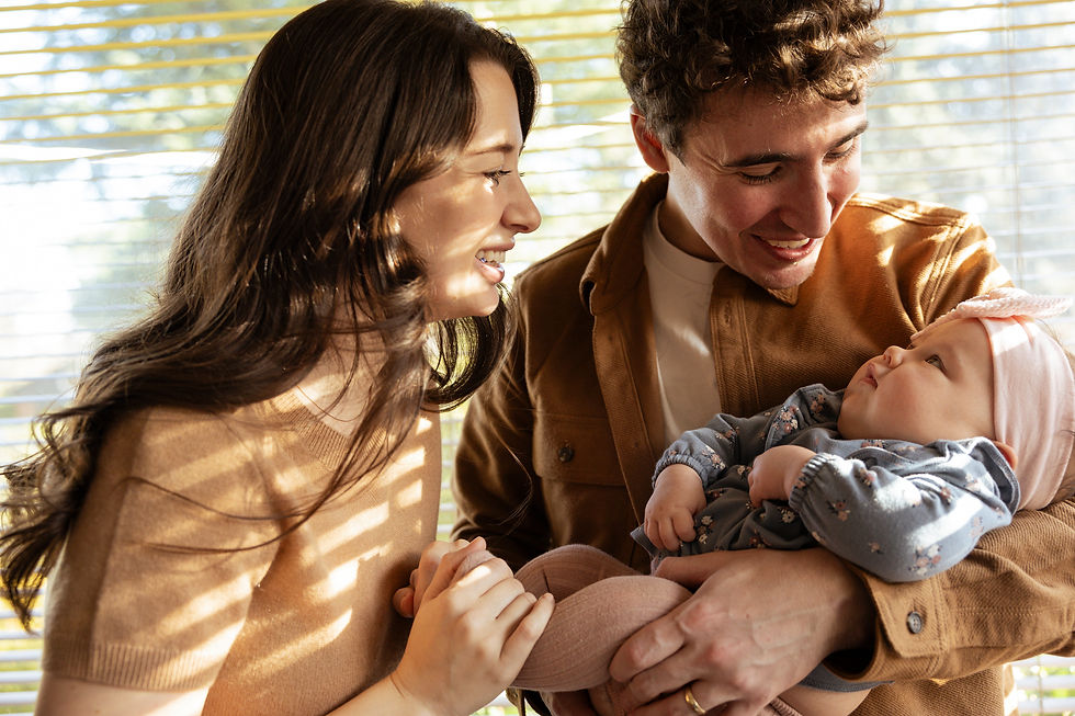 mother and father grinning at their daughter; father is holding her