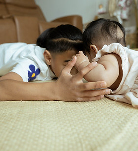 pre-teen boy looks at his baby sister while they lay their bellies on the floor