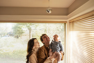 mother, father, and daughter smile while they look up at a disco ball