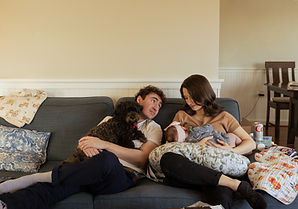 a father looks at his wife, who is feeding their baby daughter