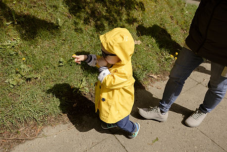 little wearing a yellow hooded rain jacket points at something in front of her