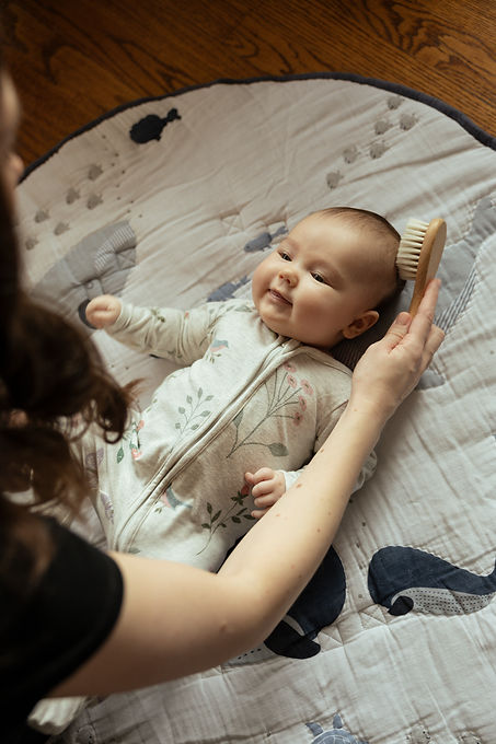 baby girl looking up at her mom, as mom brushes her hair