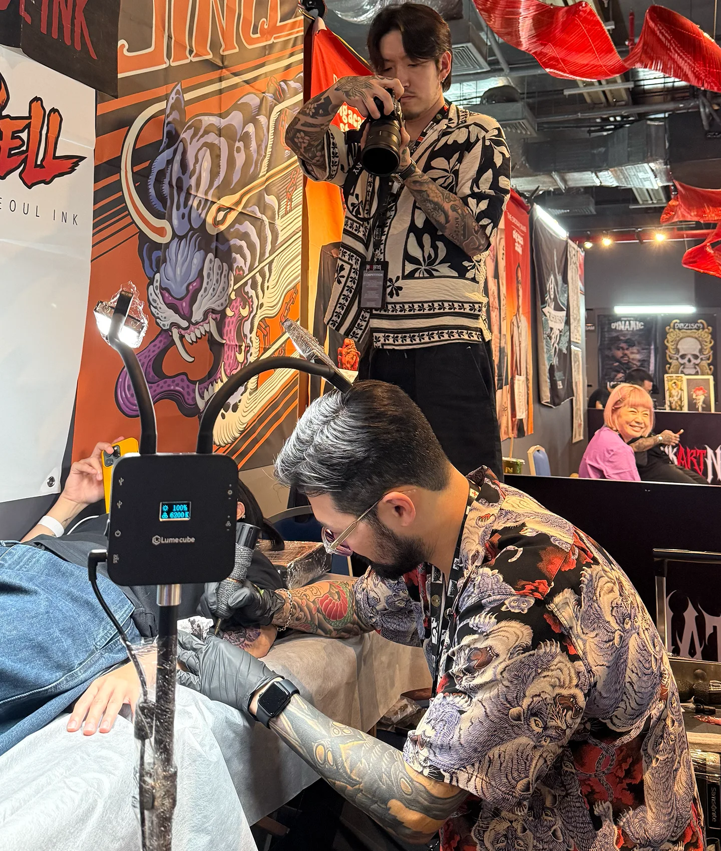 Seoul Ink Tattoo artist JinQ tattooing a client live on stage at Ink Art Nation Vietnam 2026, photographer documenting the session