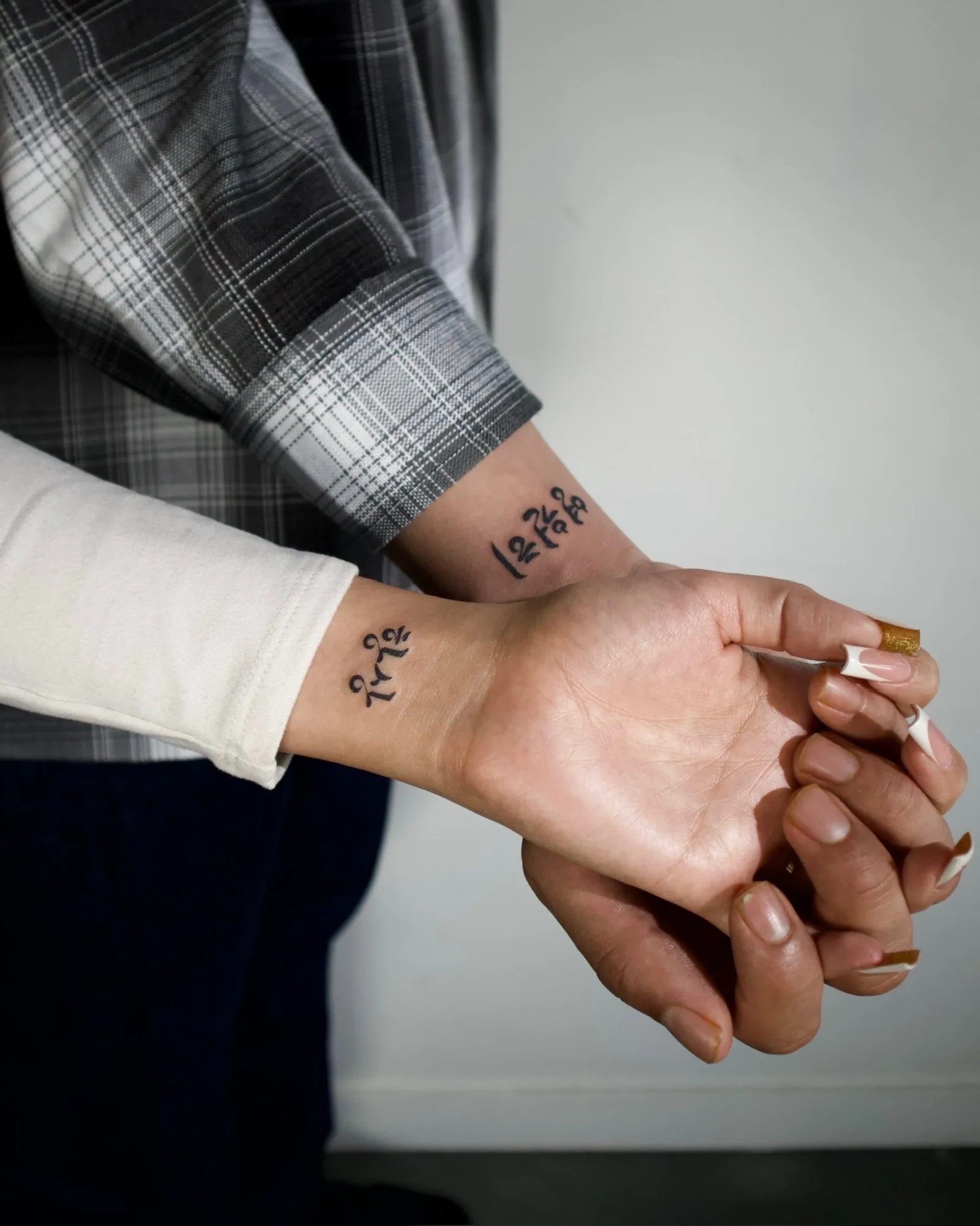 Matching fineline couple tattoos on both forearms — each arm features Korean Hangul text, abstract geometric symbols, and minimalist line drawings in a coordinated set. Seoul Ink Tattoo, Gangnam, Seoul, South Korea.