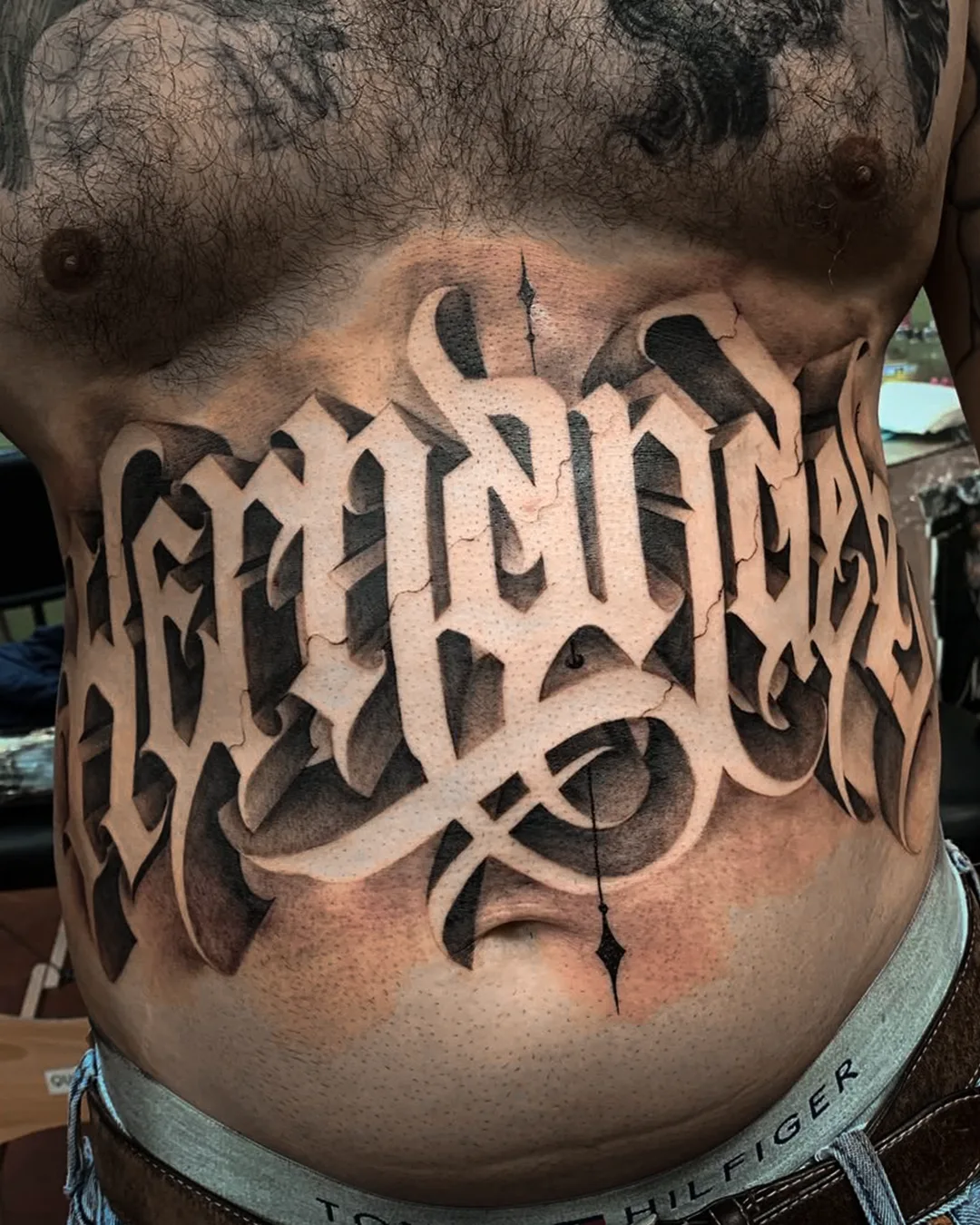 Bold black and grey custom lettering tattoo wrapping across a client's chest, designed by Mystik during his guest spot at Seoul Ink Tattoo Gangnam, Seoul South Korea