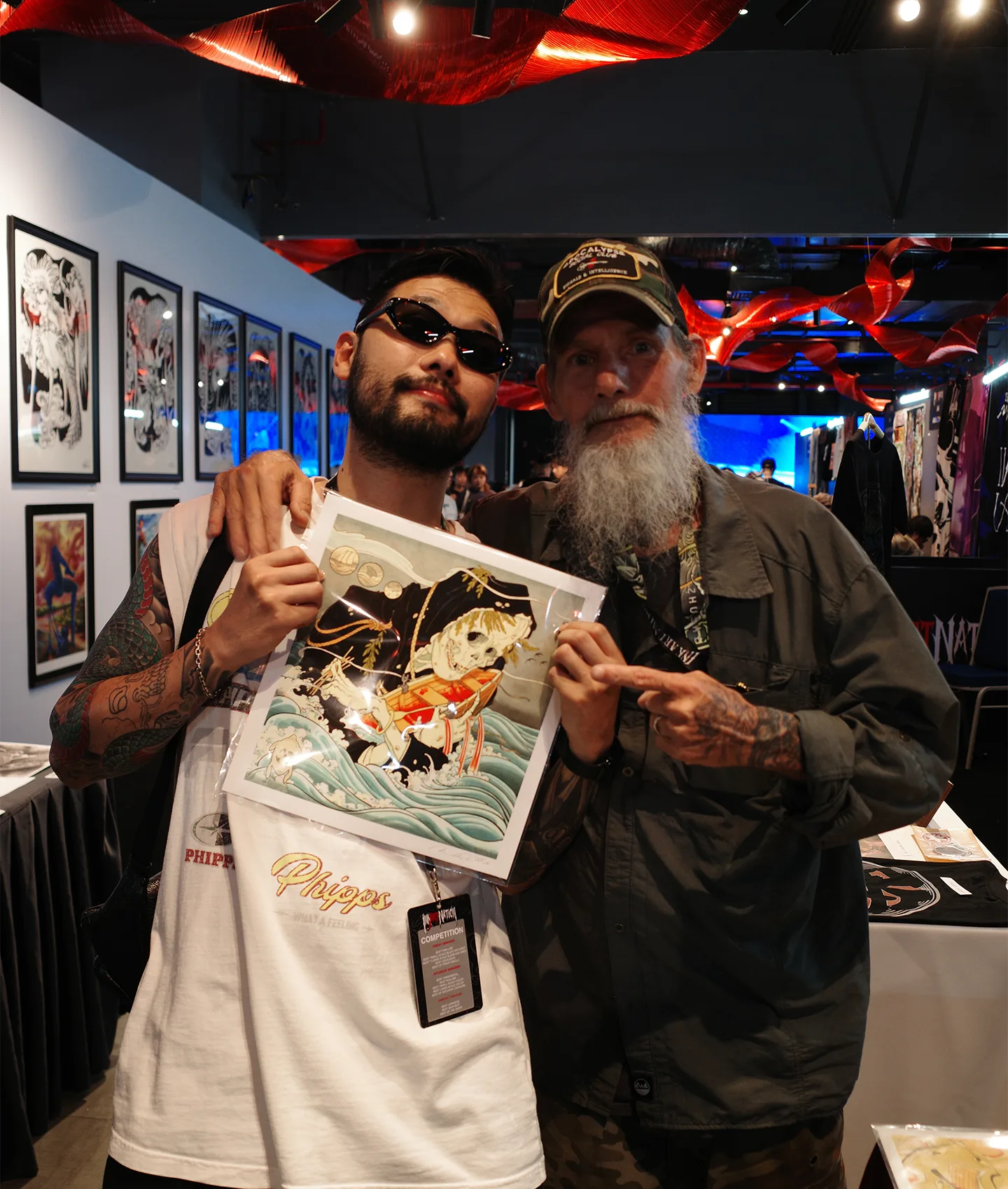 Seoul Ink Tattoo artist posing with a fellow tattoo artist holding a Japanese-style illustrated print at Ink Art Nation Vietnam 2026
