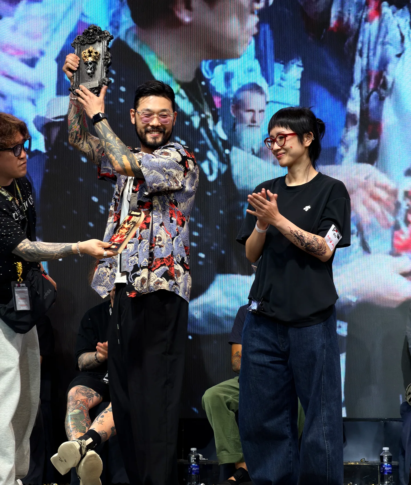 Seoul Ink Tattoo resident artist JinQ, receiving an award trophy on stage at Ink Art Nation Vietnam 2026