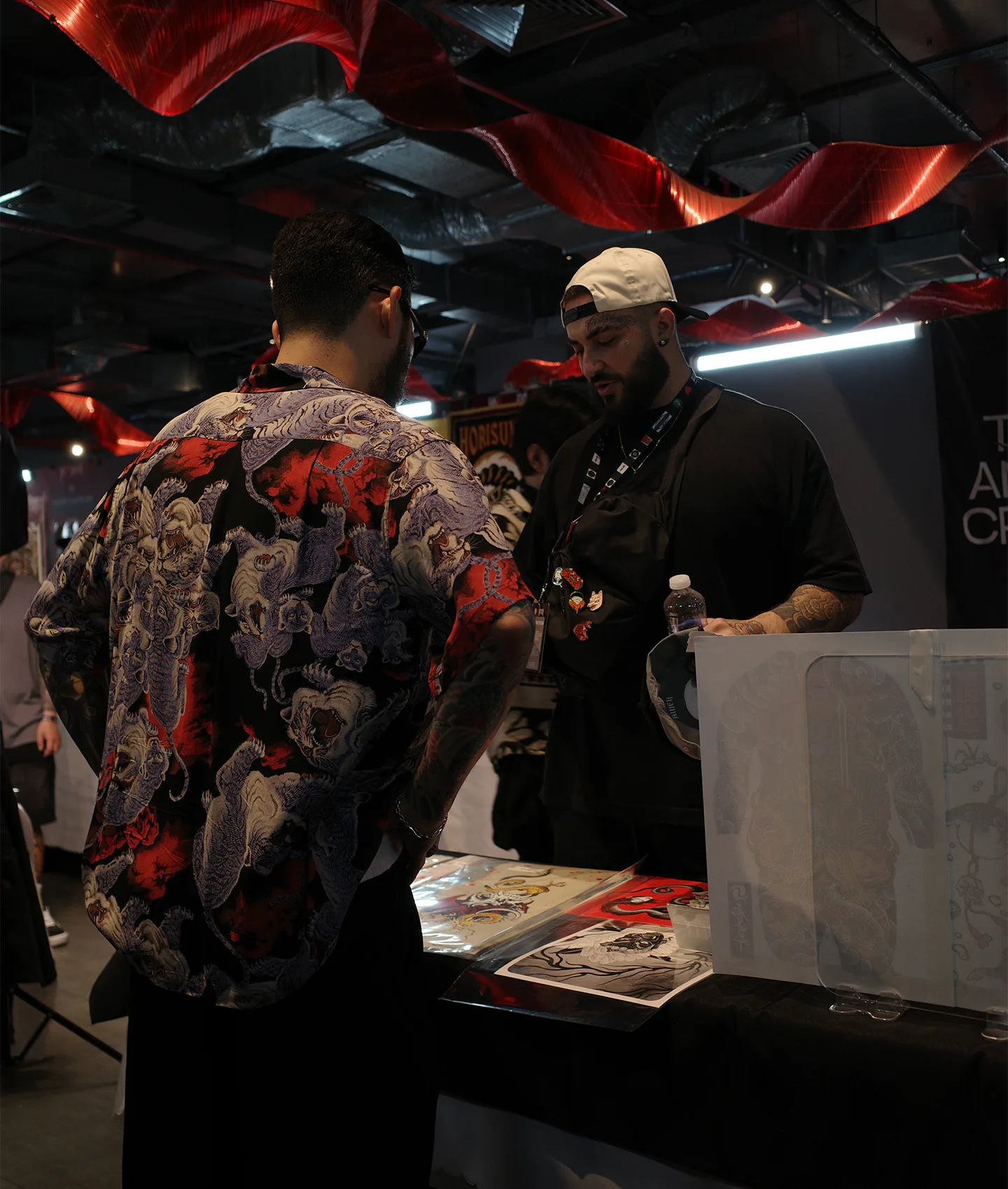 Seoul Ink Tattoo artist consulting with a client over flash art prints at Ink Art Nation Vietnam 2026
