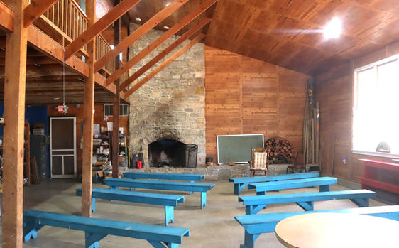 Rustic interior of a lodge with blue benches and a large stone fireplace.