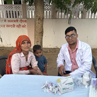 A young mom holds a bandage after her blood draw. Her son and the doctor are there.