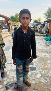 A boy sits on a clinic stool wearing no shoes.