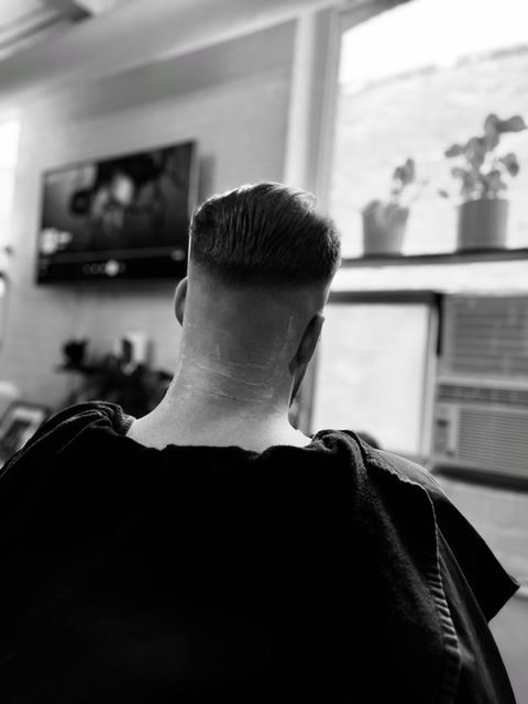 Man receiving a professional haircut from The Groomed Society's mobile barbering service, showcasing expert grooming and personalized care in a convenient, on-site setting.