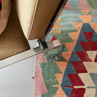 Verschoten leren designstoel op een kleurrijk kelimkleed
