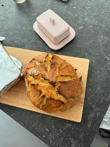 Zelfgebakken ambachtelijk brood op een plank met stenen aanrecht en een design roze botervlootje. Bracht mij tot een creatieve bak-challenge voor buurtparticipatie Amsterdam. Kolenkitbuurt.