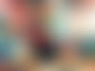 Desk with computer, camera, and stationery in colorful room. Giant Rubik's Cube in the background, vibrant mood with playful decor.