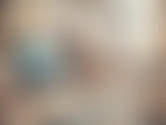 A loft with a large origami swan beside a computer showing a swan image. Smaller swans cover a wooden desk; large windows in the background.