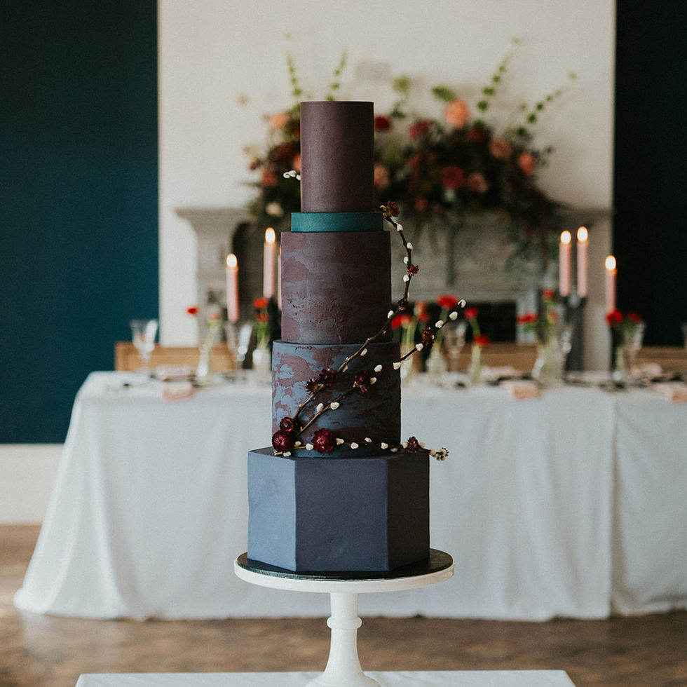 Dark modern wedding cake with velvety purple and burgundy hues stood on a cake stand at Harbour Hotel Newquay