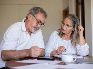 Mature couple reviewing finances at home, showing concern and unity during uncertain times.