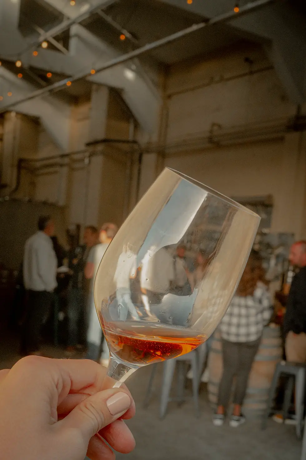 A wine event in an industrial winery in California with a glass of wine in the foreground