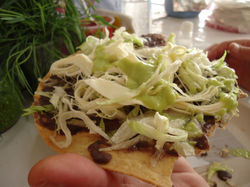 Tostada de frijol con lechuga y quesillo