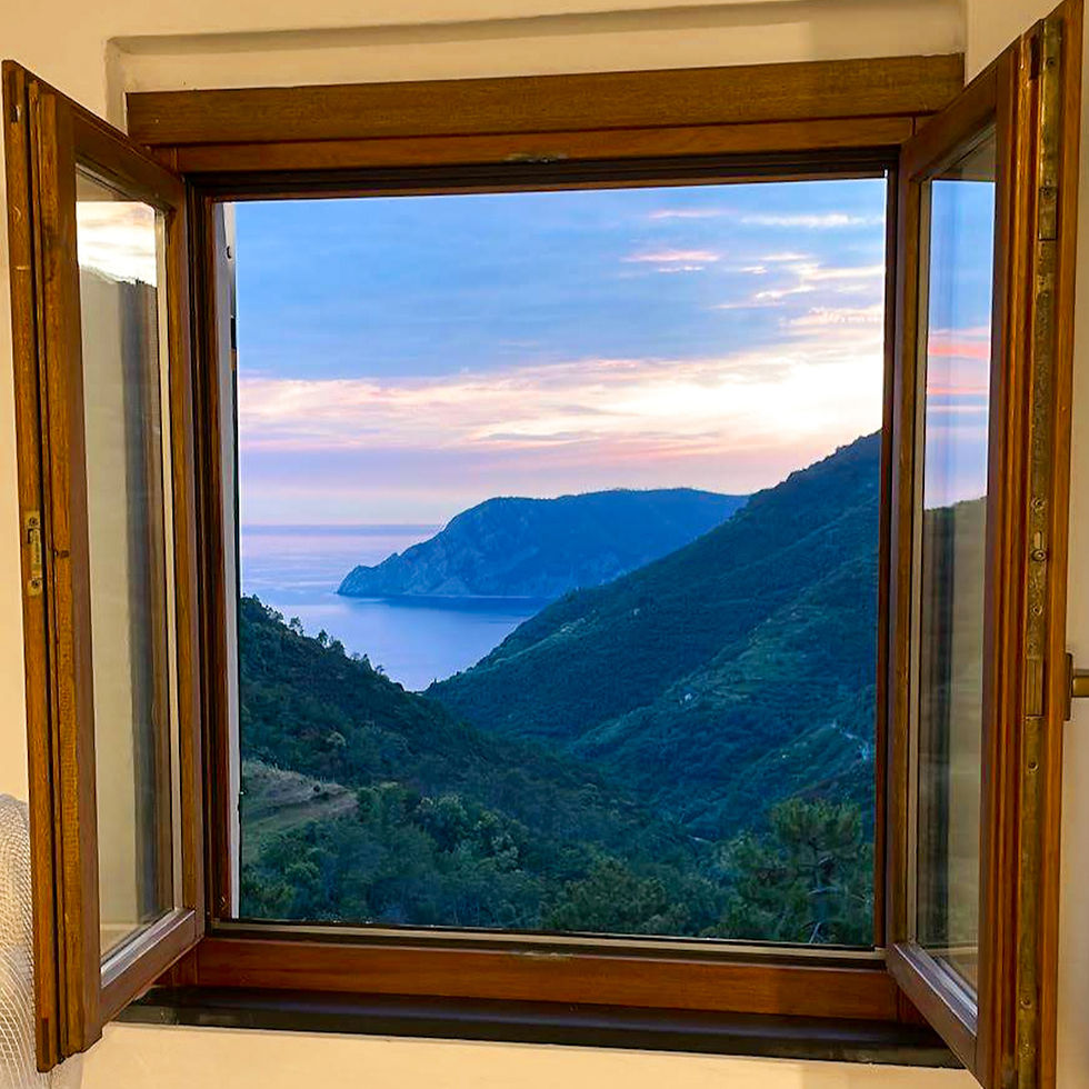 Open window frames a serene view of green hills and a distant sea under a colorful, cloudy sky. Peaceful, natural setting. vernazza cinque terre italy