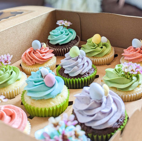 Cupcakes with bright frosting and spring-themed decor (including live flowers).