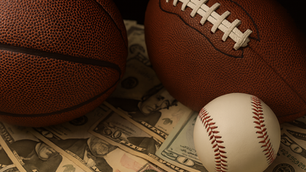 A basketball, football, and baseball are all on top of money