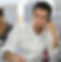 A gentleman wearing white shirt has a headset plugged on looking down on his keyboard.